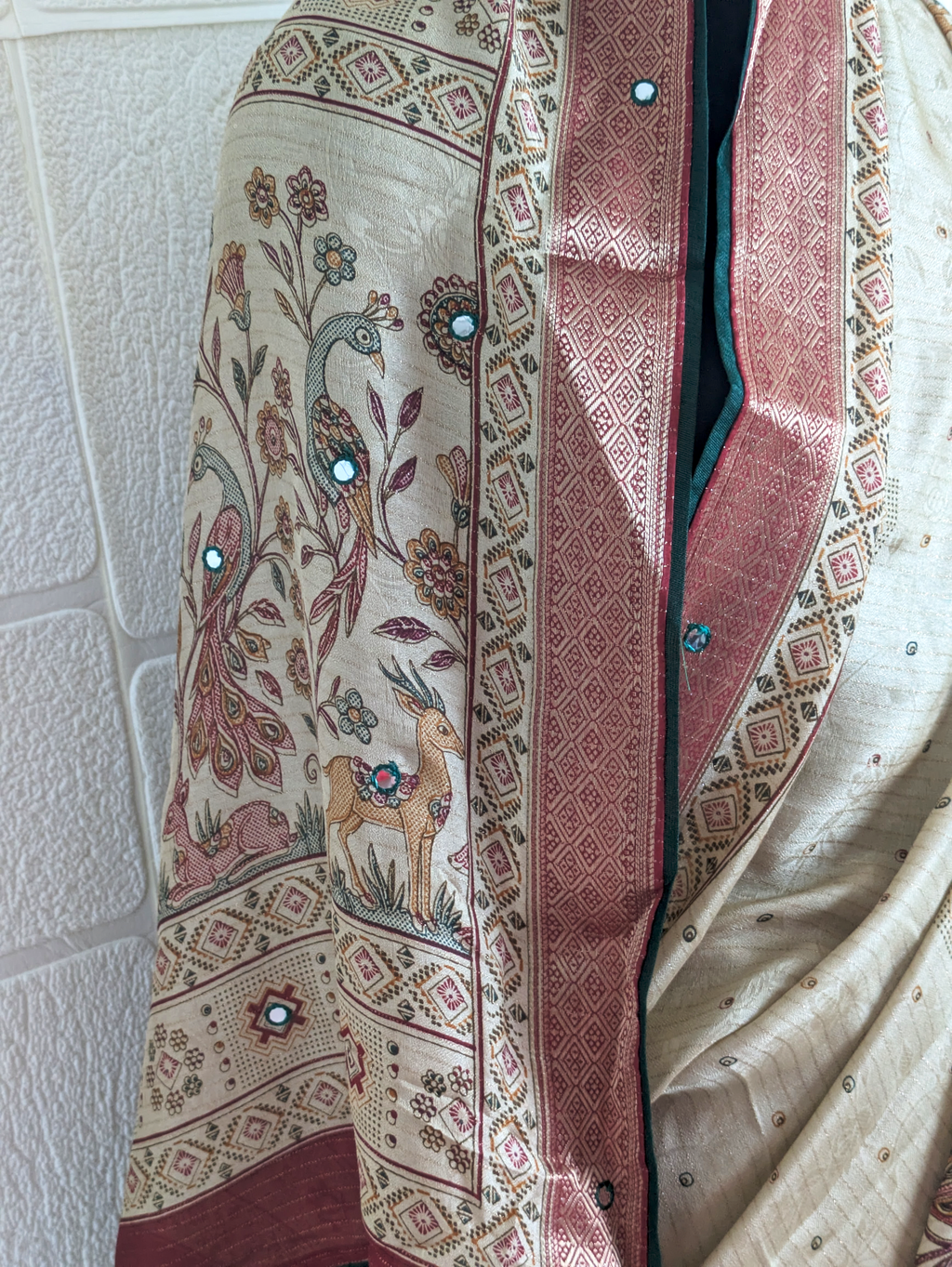 Traditional beige silk saree featuring peacock, deer, floral motifs, and rich maroon zari border