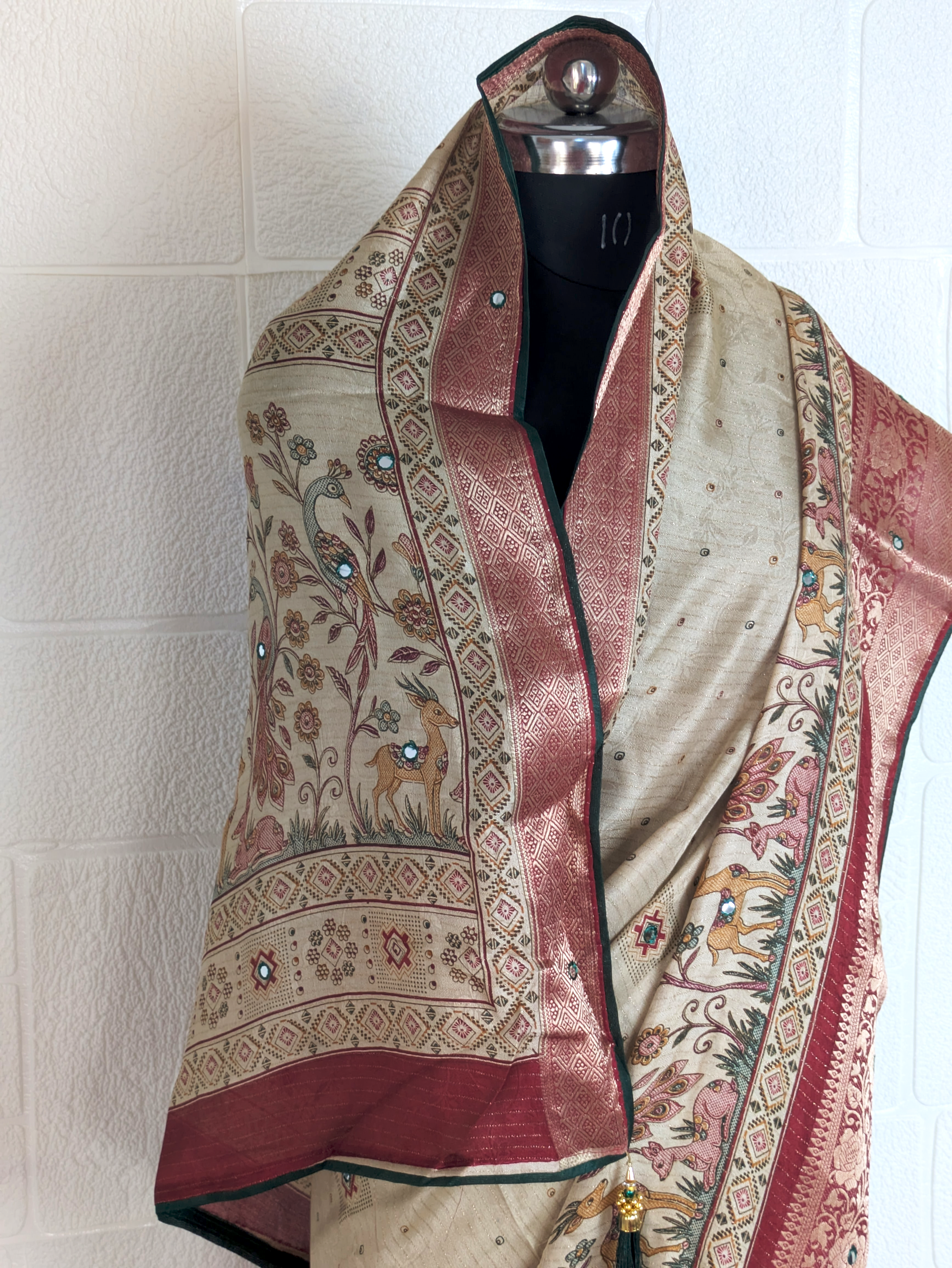 Handloom-style beige saree with peacock artwork, woven pallu, maroon brocade border, and stone embellishments