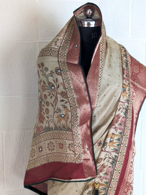 Handloom-style beige saree with peacock artwork, woven pallu, maroon brocade border, and stone embellishments