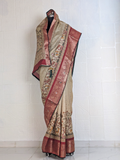 Full-length beige silk saree with peacock and deer motifs, maroon zari border, and heritage-inspired woven design