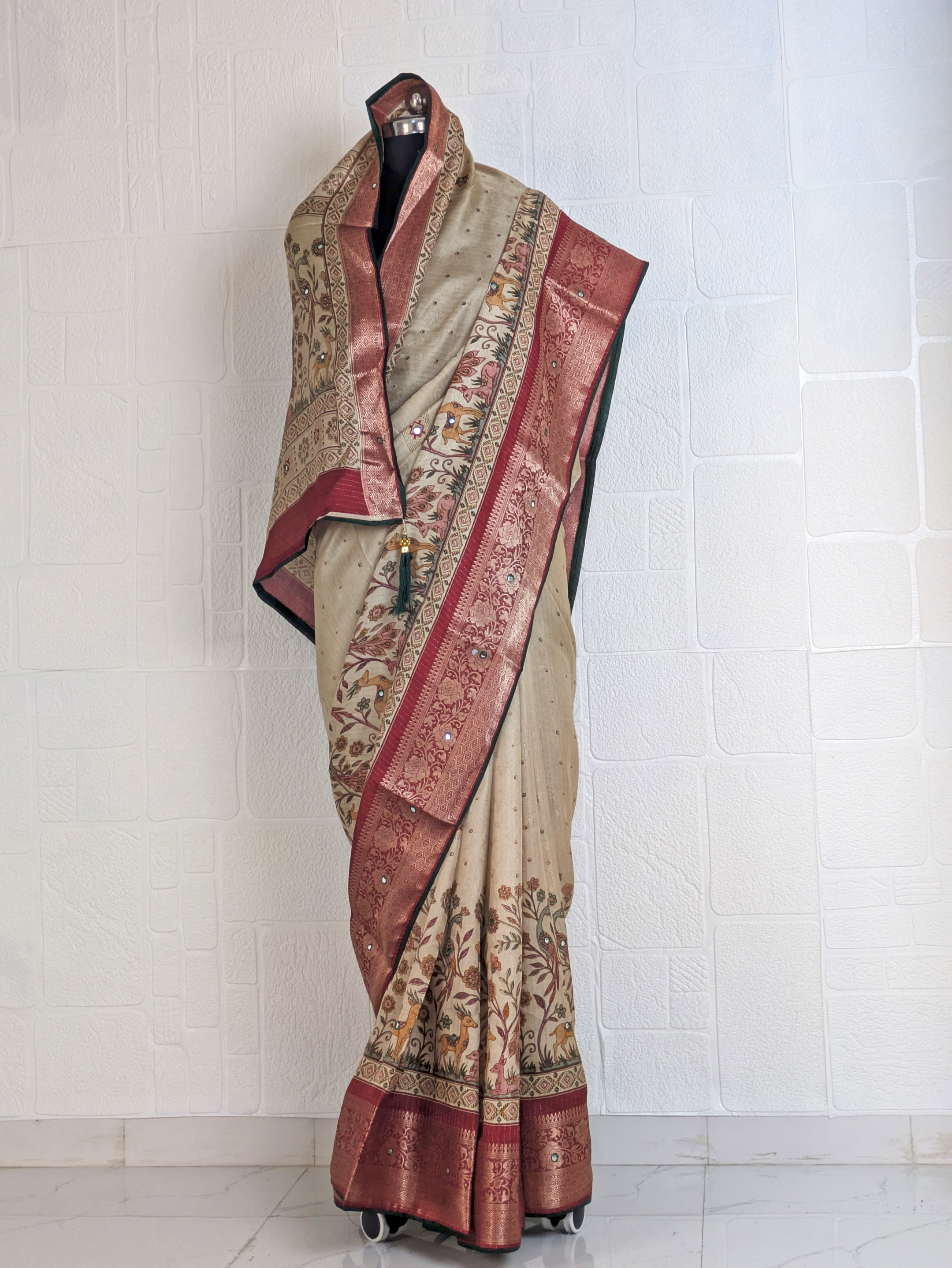 Full-length beige silk saree with peacock and deer motifs, maroon zari border, and heritage-inspired woven design